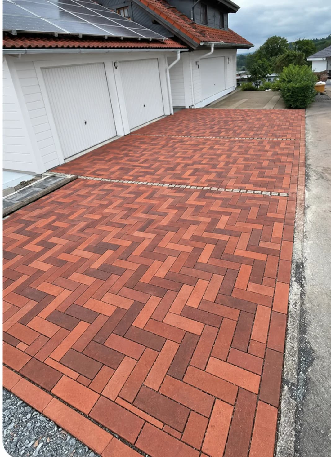 Sorgfältig verlegtes rotes Pflaster vor einer Garage